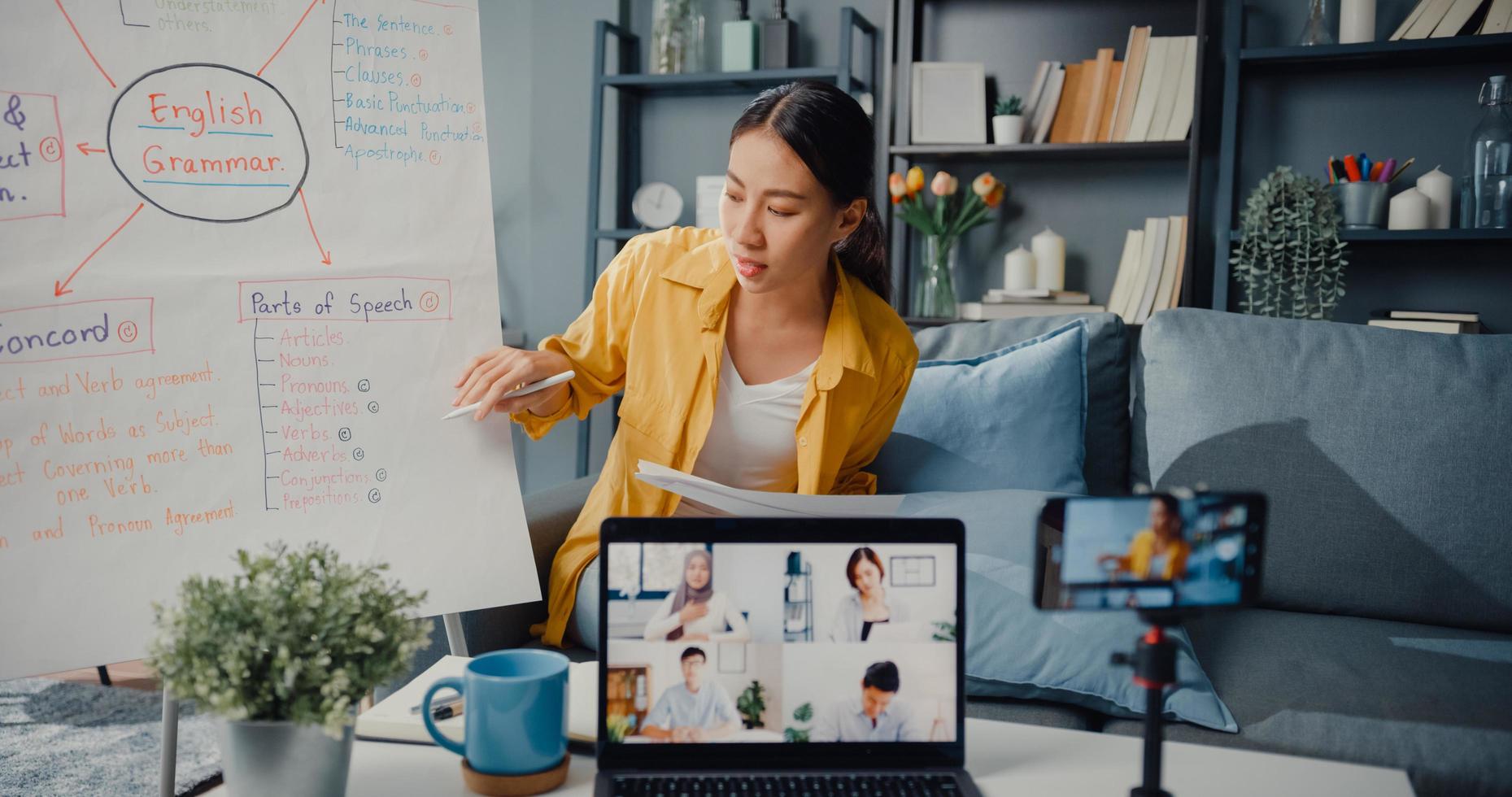 Jovencita de Asia, profesora de inglés, videoconferencia, llamada en el teléfono inteligente, hablar por cámara web, aprender, enseñar en el chat en línea en casa foto