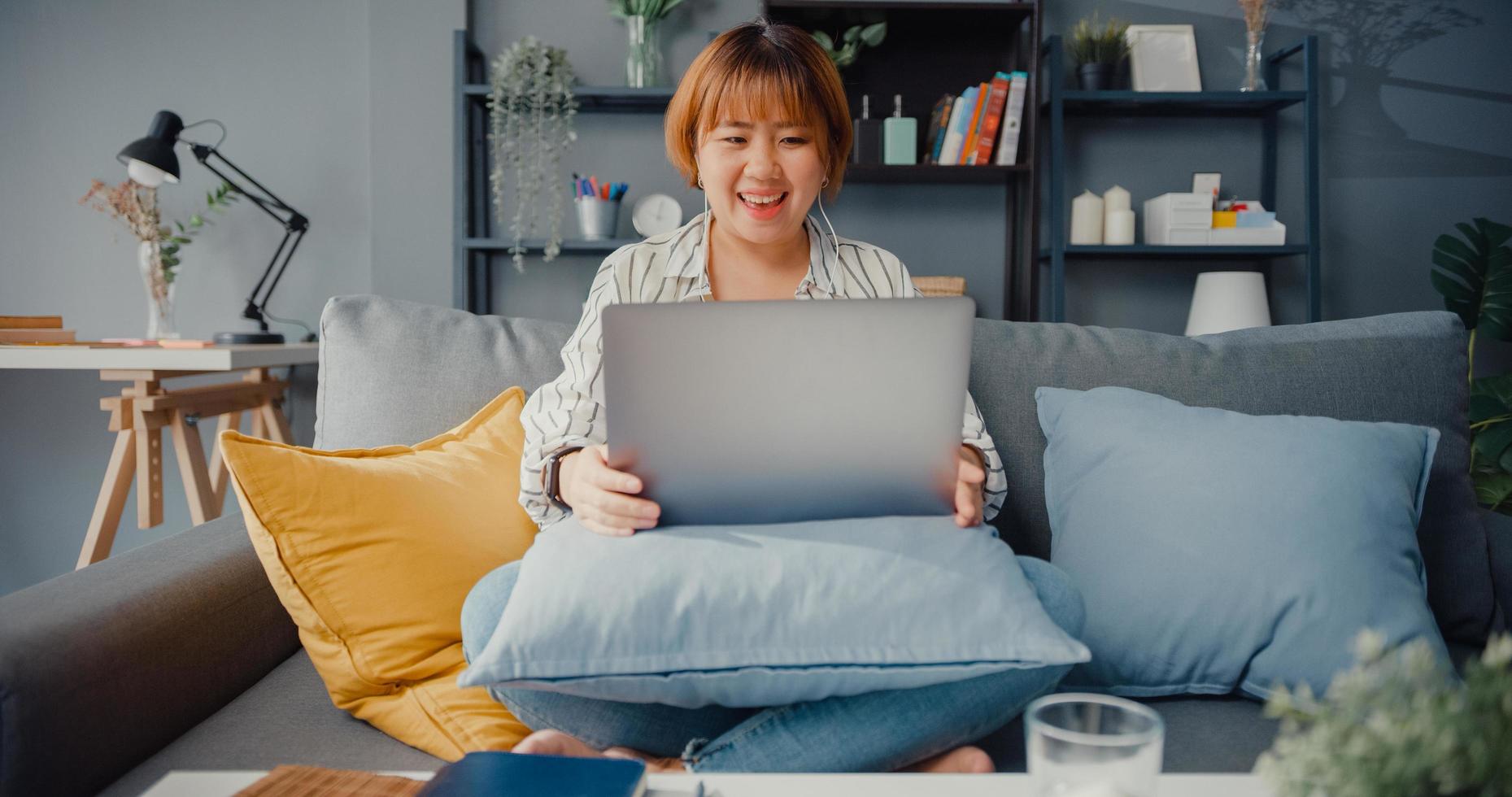 Asia empresaria usando laptop hablar con colegas sobre el plan en videollamada mientras trabaja desde casa en la sala de estar foto
