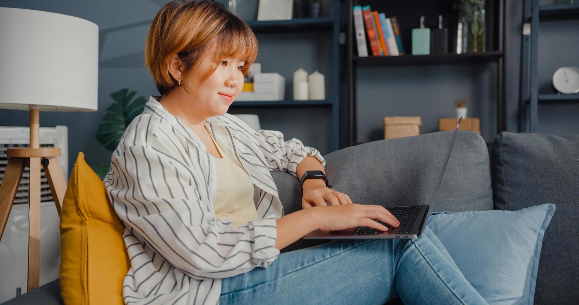 Freelance Asia lady casual wear using laptop online learning in living room at house photo