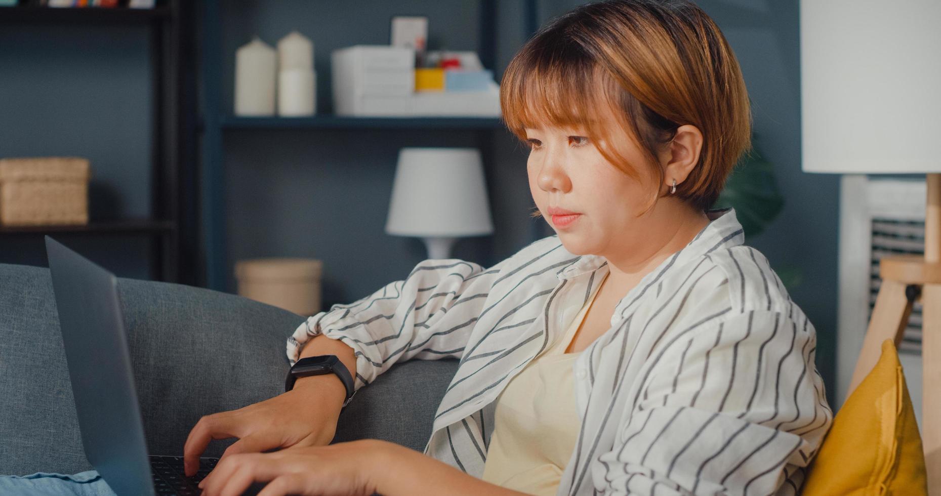 Freelance Asia lady casual wear using laptop online learning in living room at house photo