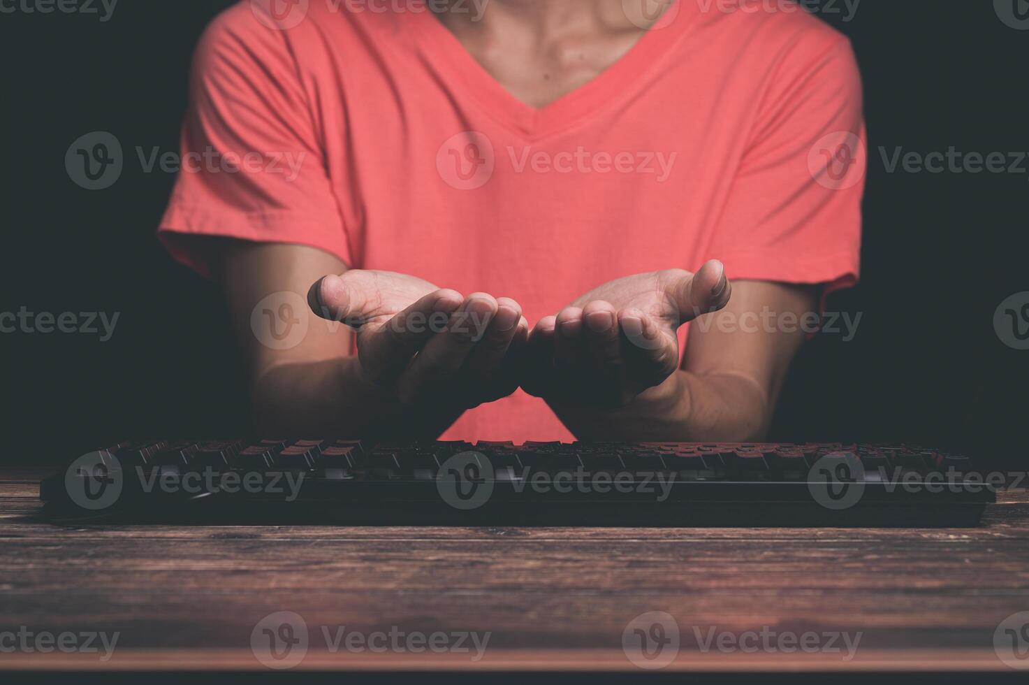 A person sitting at a desk with their hands out photo