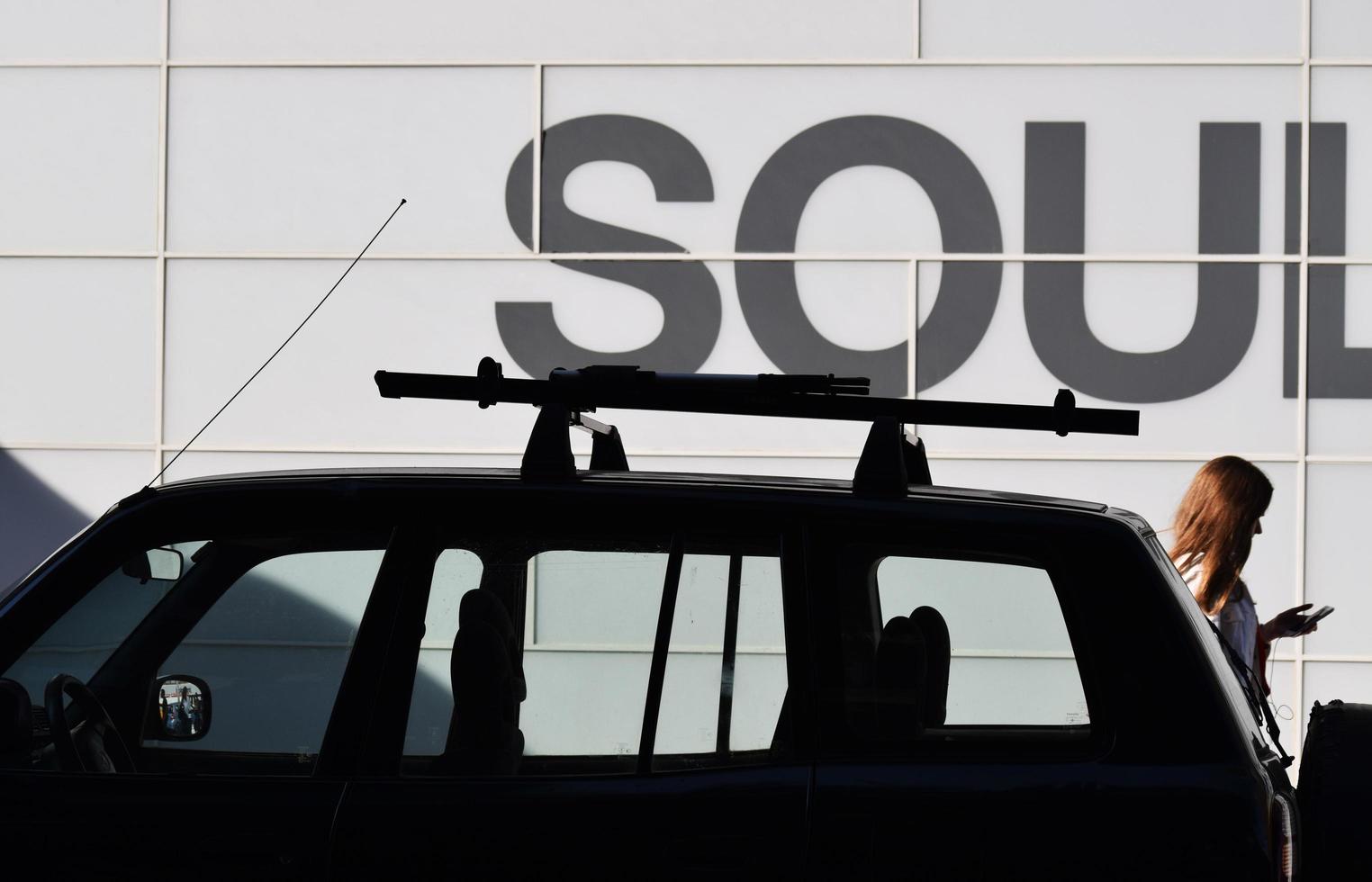 Woman passing sports utility vehicle while walking beside building photo