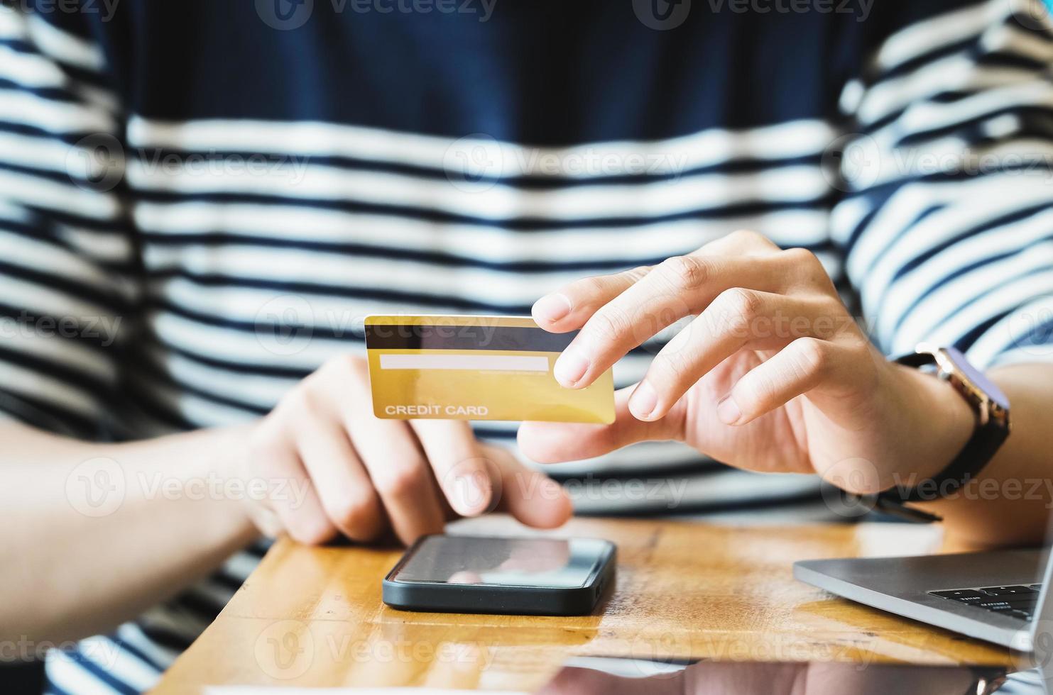 Pay online with hand holding a credit card and using a smartphone photo