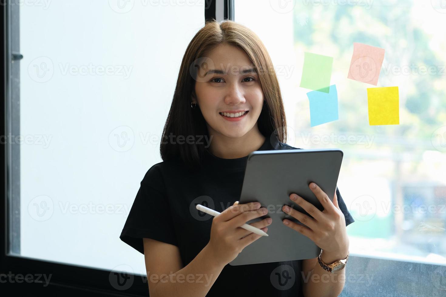 A female company employee uses a tablet and notepad to analyze company budgets photo