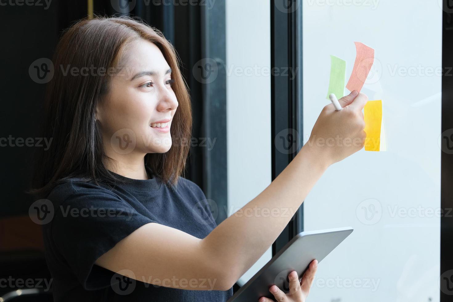 una empleada de la empresa que usa el bloc de notas y la tableta para analizar los presupuestos de la empresa foto