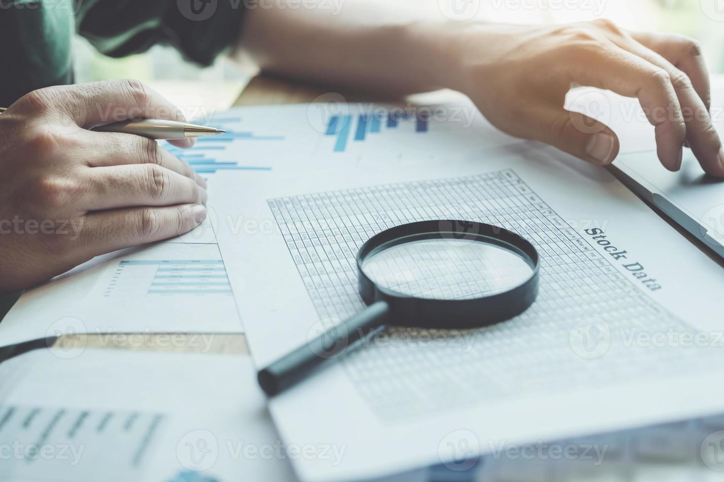 Businessman using magnifying glass to review balance sheet photo