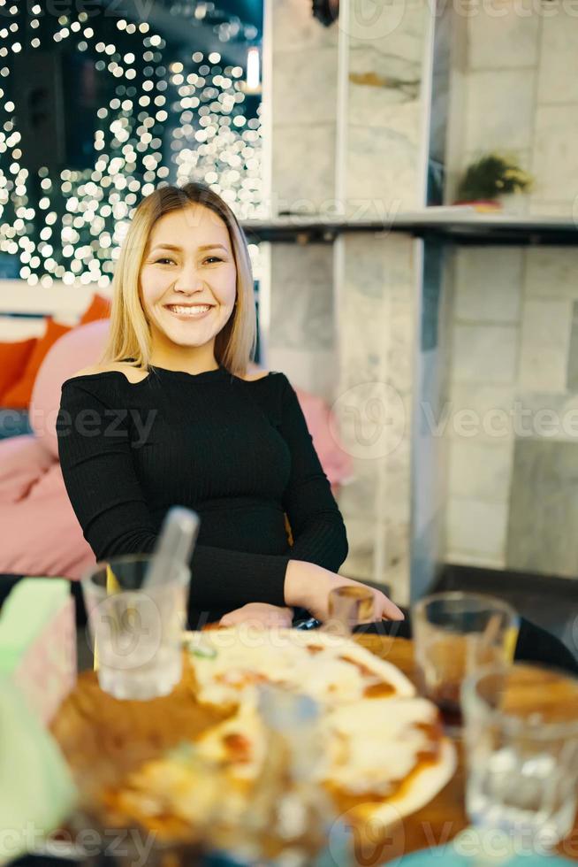 Impresionante chica sentada en una silla en el café y sonríe foto