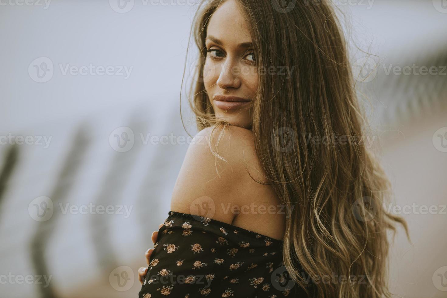 Joven mujer morena de pelo largo caminando por la orilla del río foto