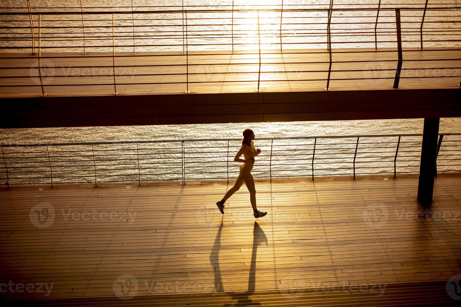 Mujer joven haciendo ejercicio para correr por el paseo fluvial foto