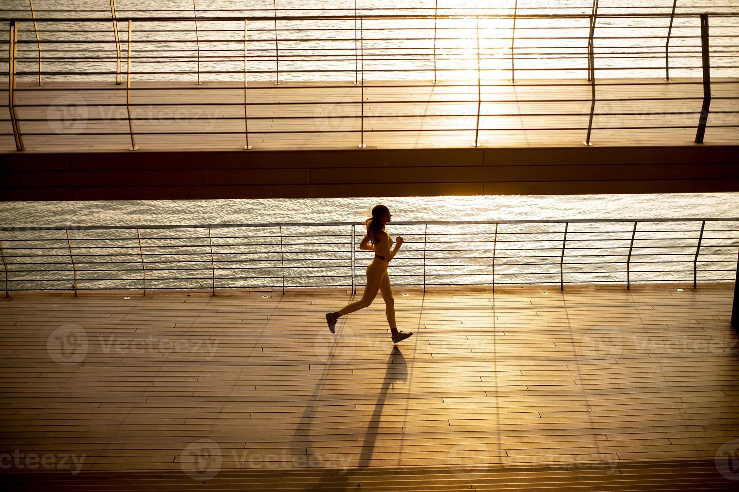 Mujer joven haciendo ejercicio para correr por el paseo fluvial foto