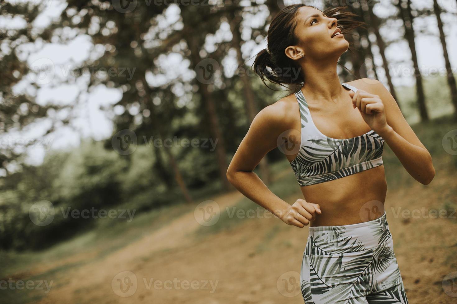 Young fitness woman running at forest trail photo