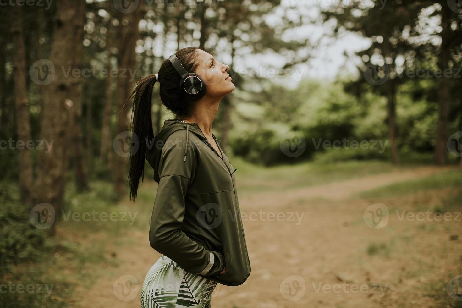 Hermosa joven corredora escuchando música y tomando un descanso después de trotar en un bosque foto