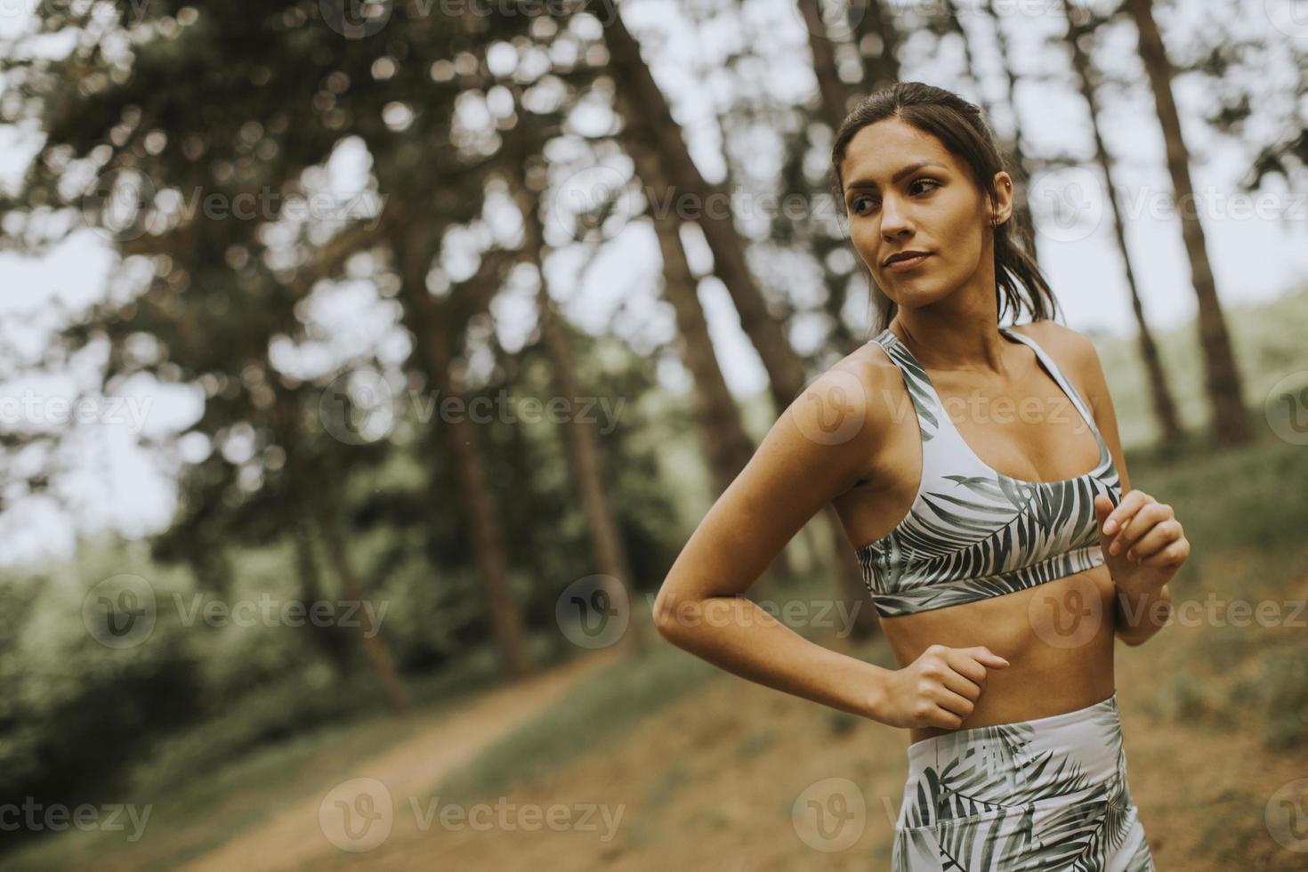 Young fitness woman running at forest trail photo