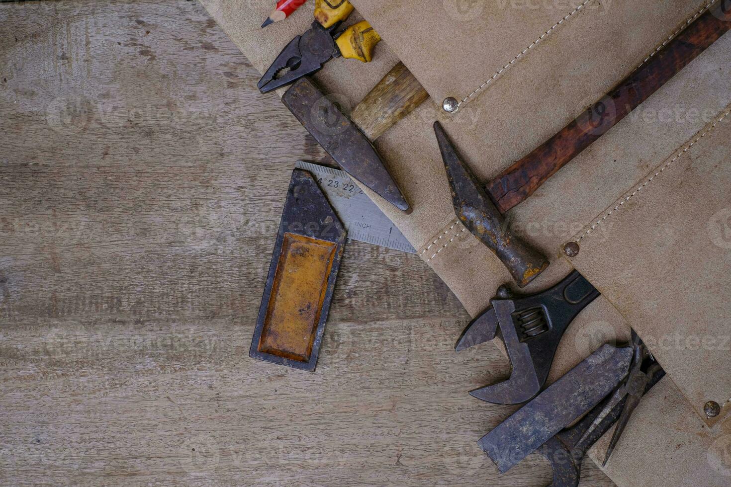 Colección de herramientas de mano antiguas para trabajar la madera en el delantal de cuero sobre un banco de trabajo de madera rugosa foto