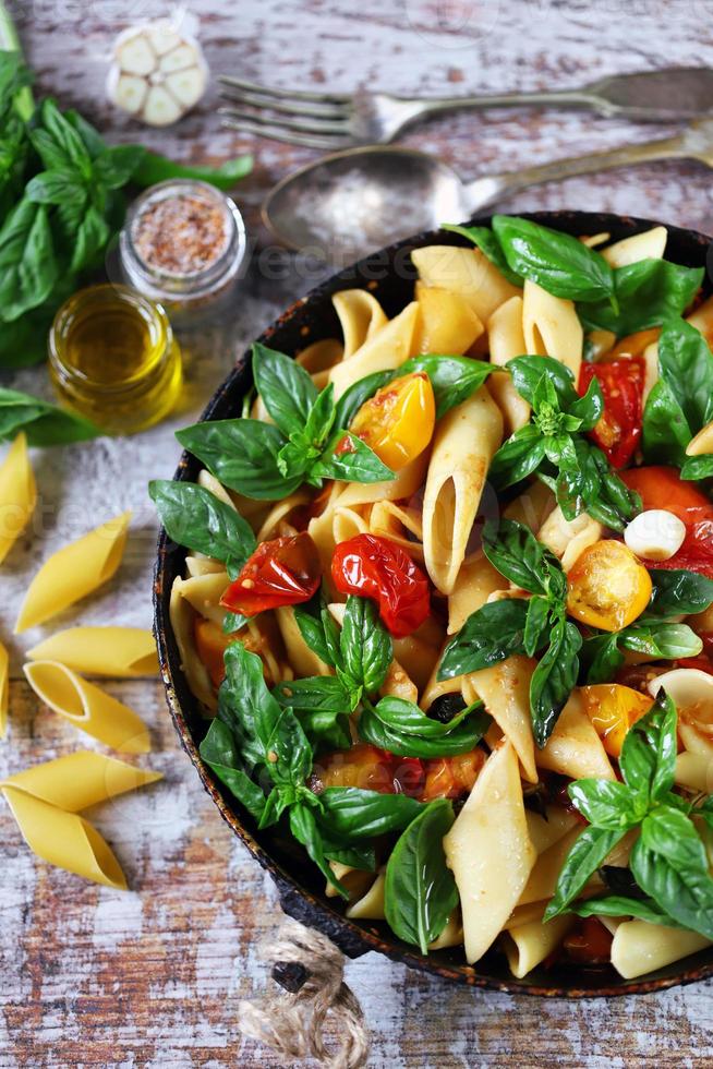 Pasta in a pan with tomatoes basil and spices photo