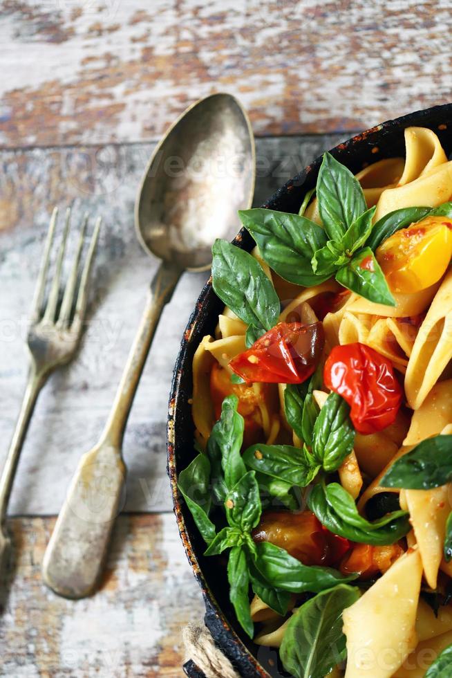 Pasta in a pan with tomatoes basil and spices photo