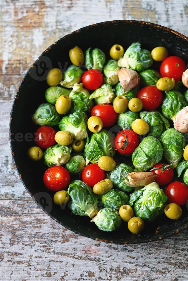 coles de Bruselas con verduras y hierbas en una sartén foto