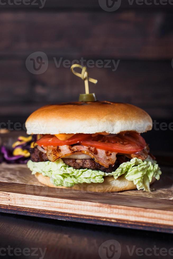 Hamburguesa con queso en una bandeja de madera en un restaurante, sobre un fondo oscuro foto