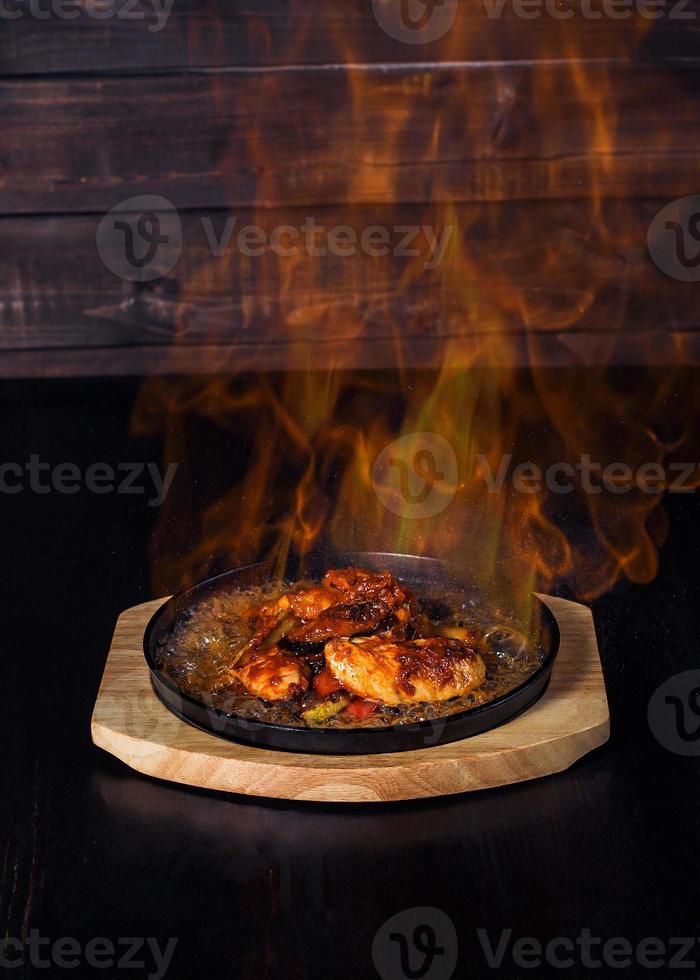 fajitos, carne en una sartén con fuego en una bandeja de madera, hermosa porción, fondo oscuro foto