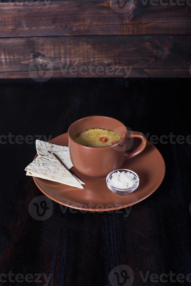 Sopa cremosa con pan de pita en un plato, hermosa porción, fondo oscuro foto