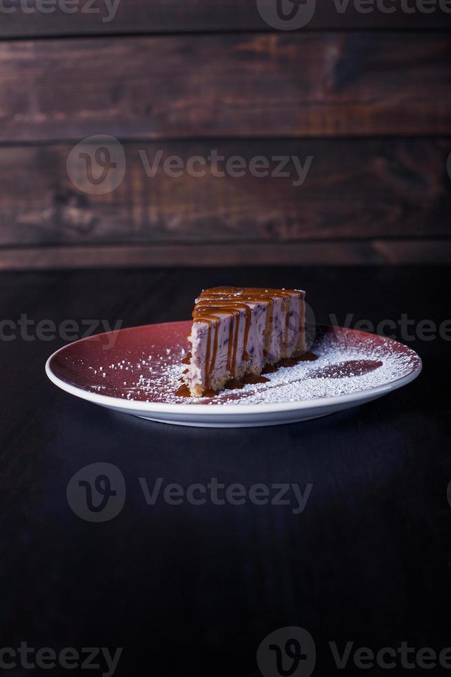 Pastel de postre dulce en un plato, hermosa porción, fondo oscuro foto