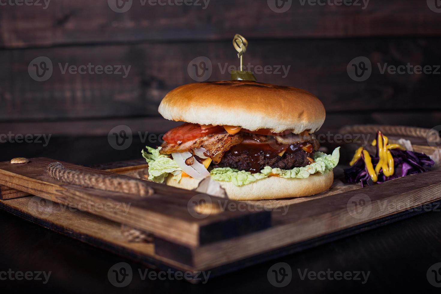 Hamburguesa con queso en una bandeja de madera en un restaurante, sobre un fondo oscuro foto