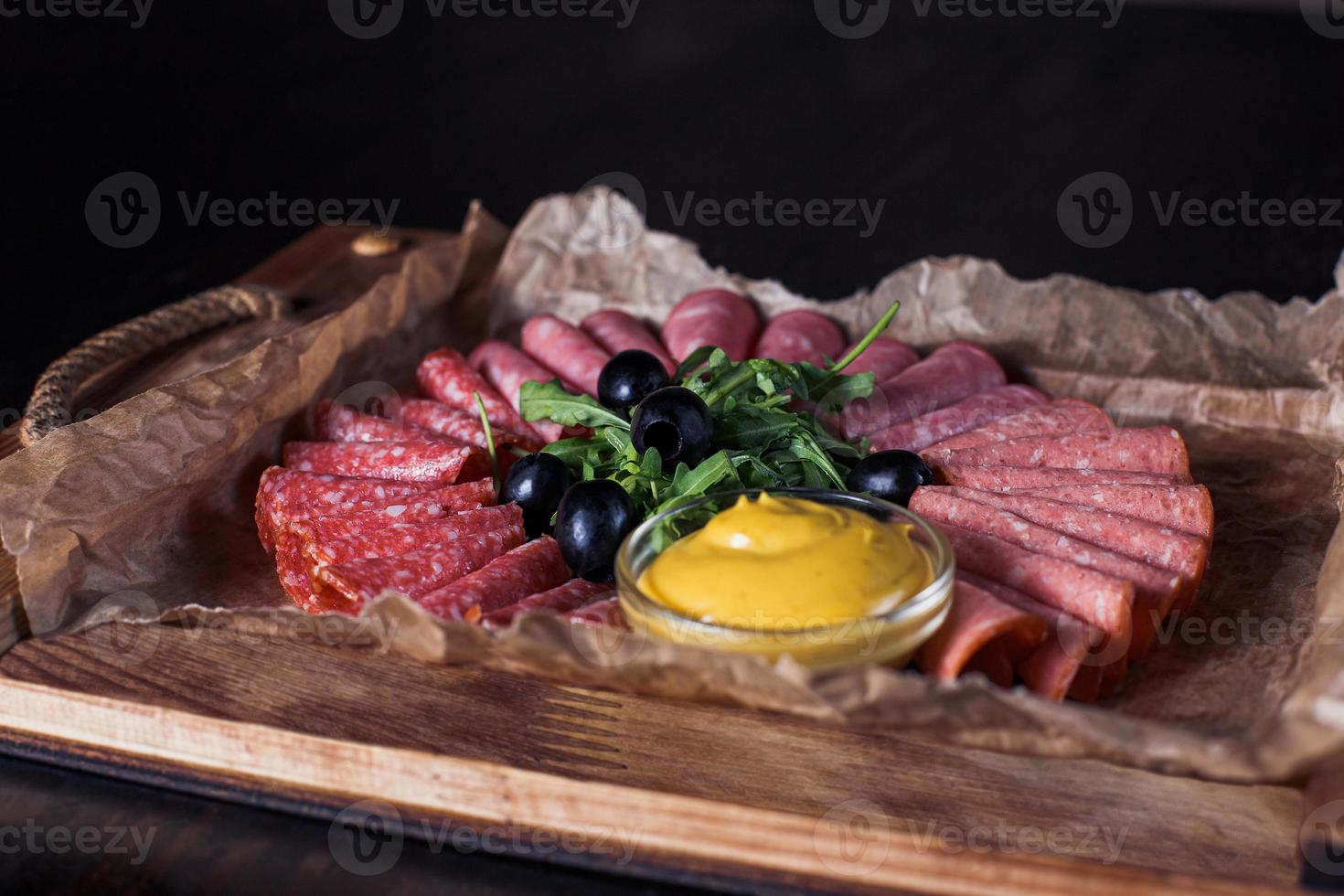 sausage cut with herbs and sauce on a wooden tray, beautiful serving, dark background photo