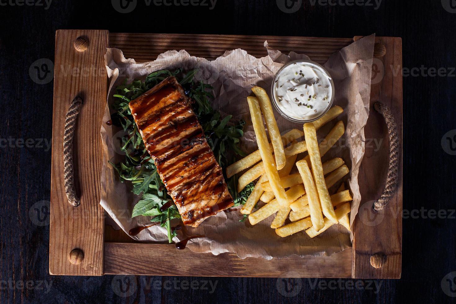 salmon fillet steak with french fries on a wooden tray, beautiful serving, dark background photo