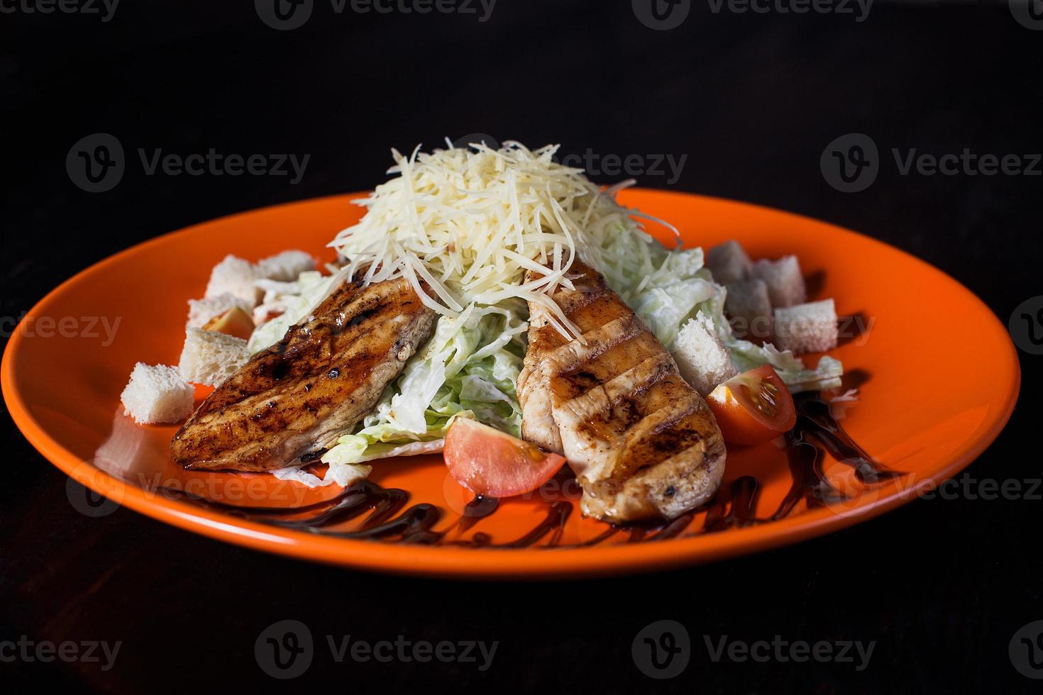 oriental salad with chicken on an orange plate, beautiful serving, dark background photo