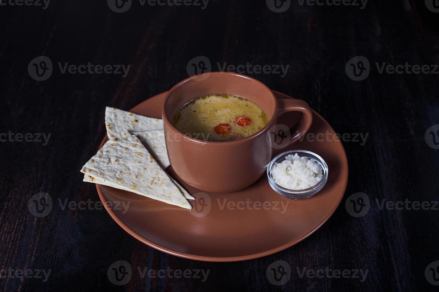Sopa cremosa con pan de pita en un plato, hermosa porción, fondo oscuro foto