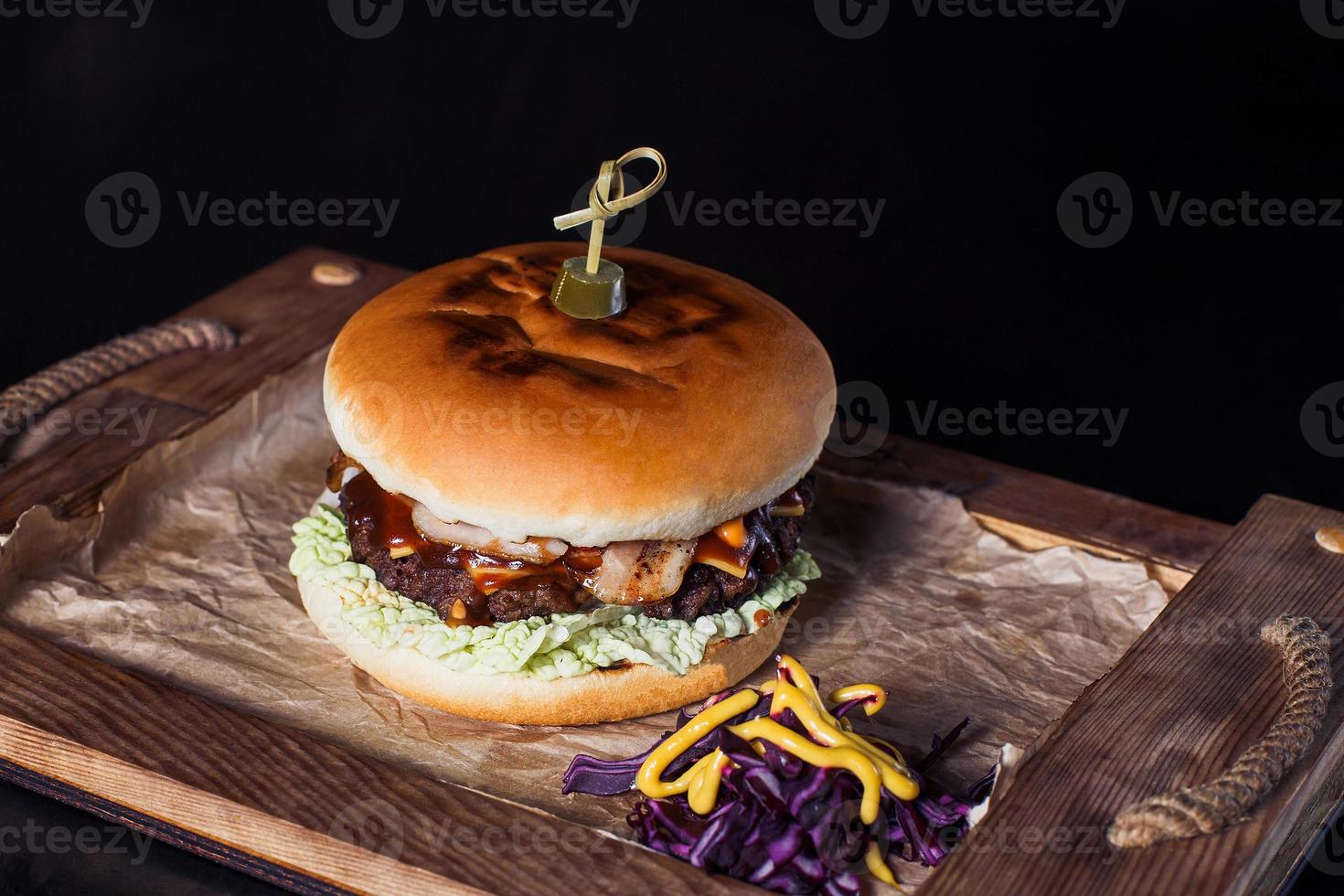 Hamburguesa con queso en una bandeja de madera en un restaurante, sobre un fondo oscuro foto