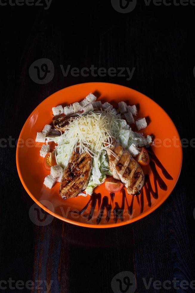 oriental salad with chicken on an orange plate, beautiful serving, dark background photo