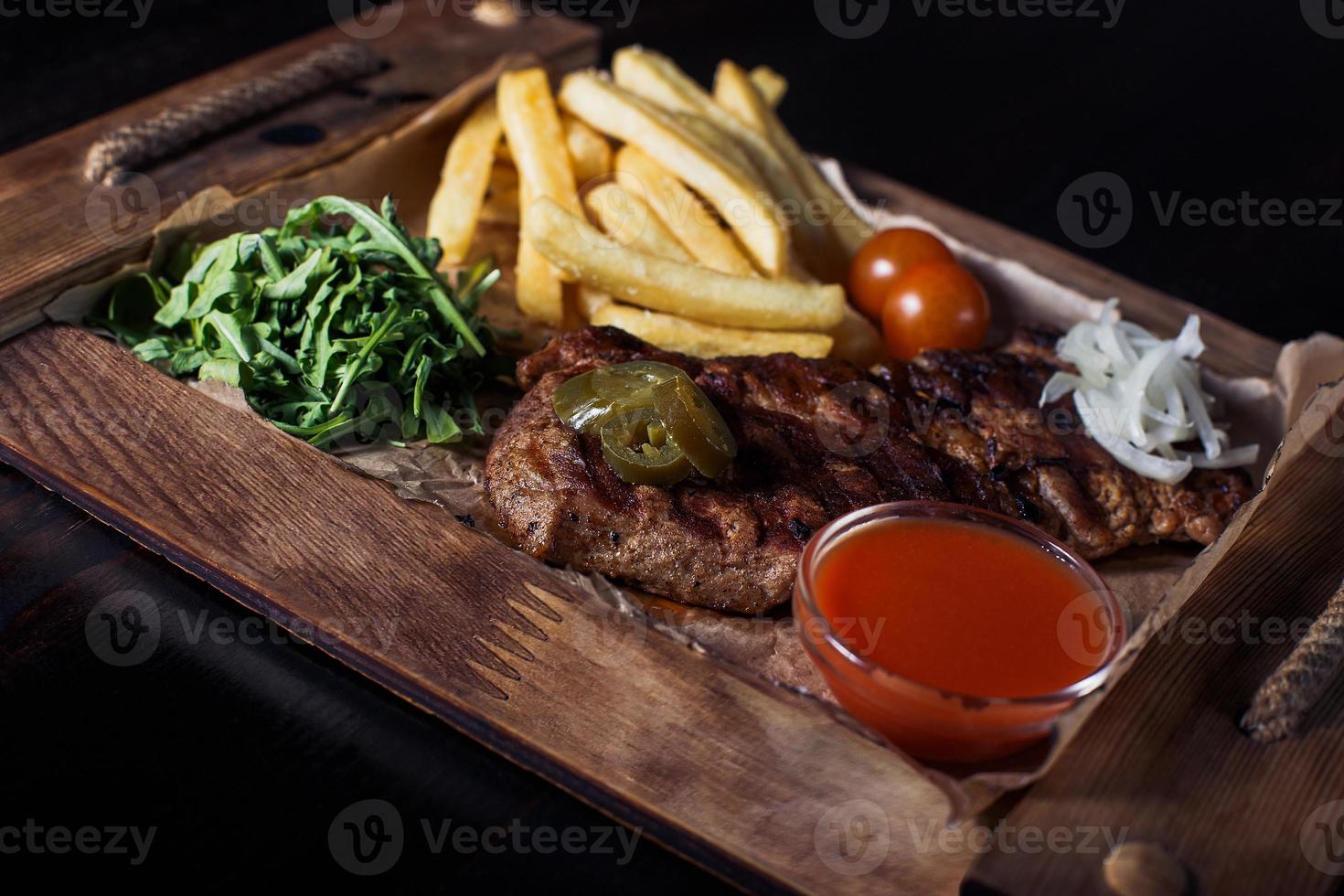 fillet steak with french fries on a wooden tray, beautiful serving, dark background photo