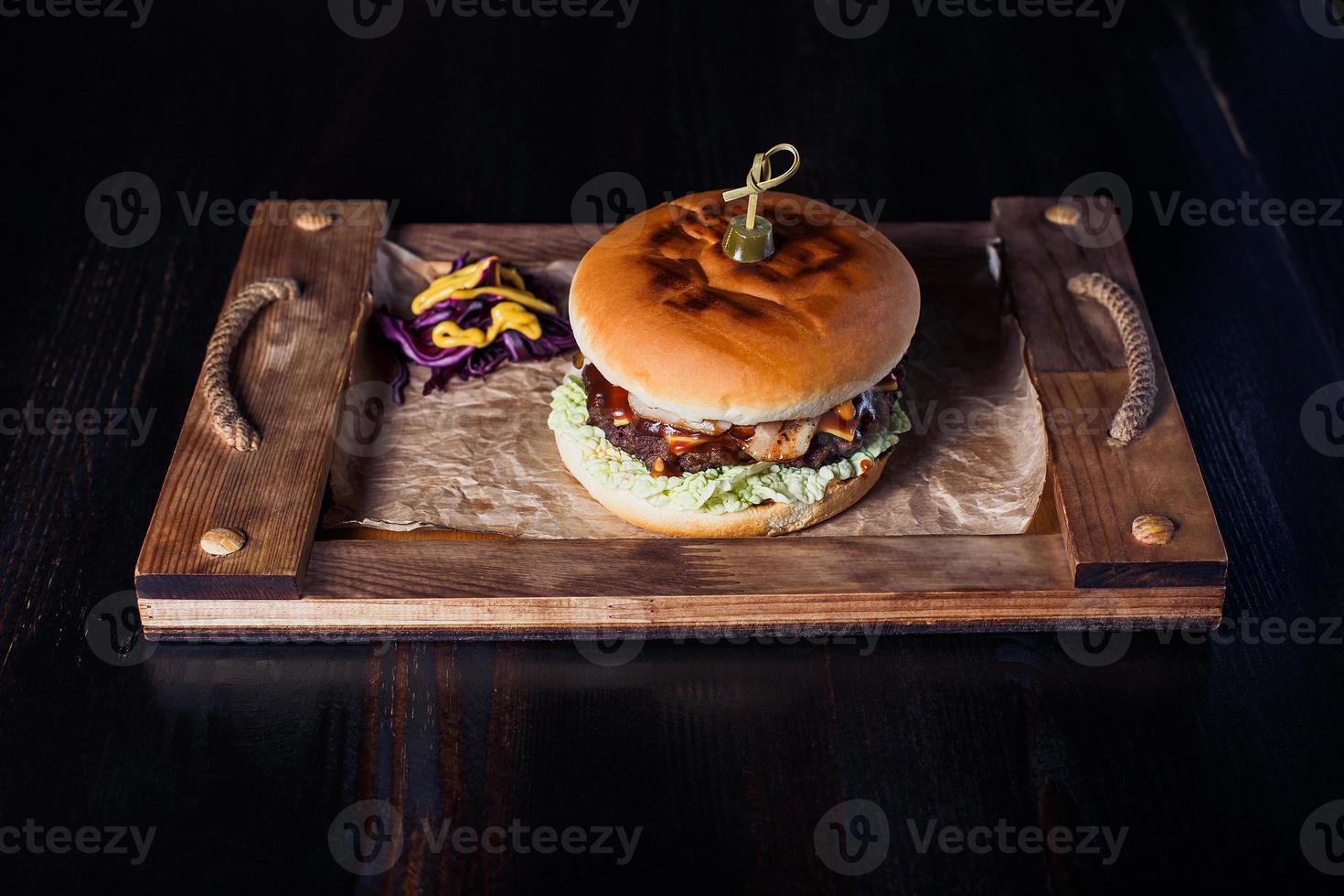 cheeseburger on a wooden tray in a restaurant, on a dark background photo