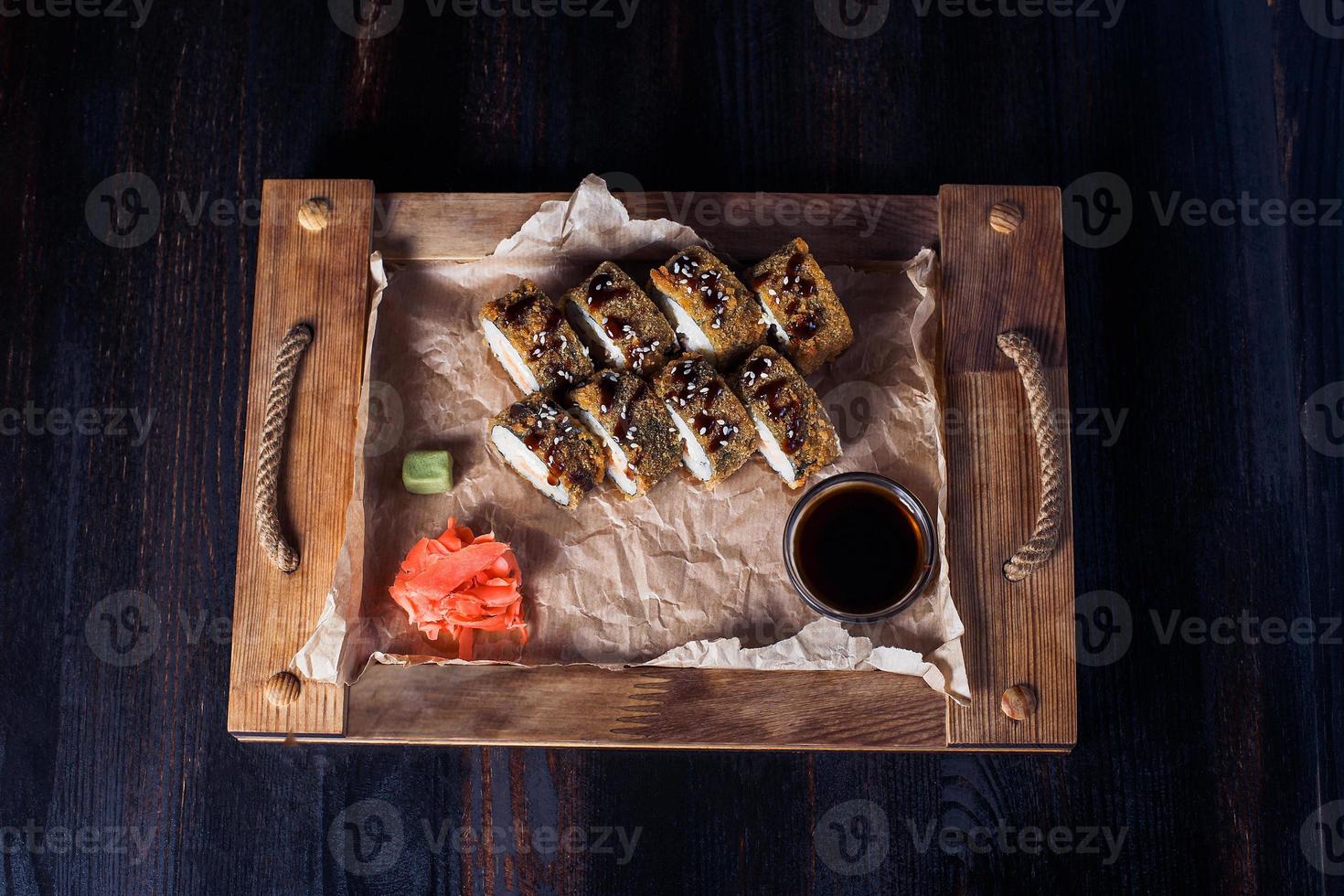 Rollos de mariscos en una bandeja de madera, hermosa porción, fondo oscuro foto