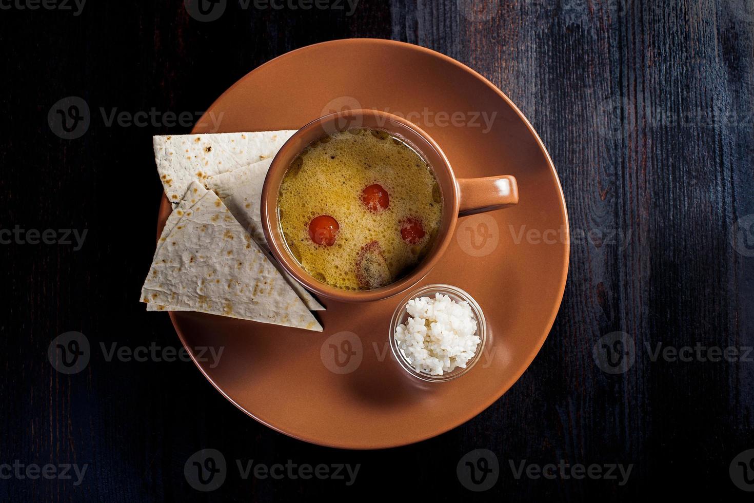 Sopa cremosa con pan de pita en un plato, hermosa porción, fondo oscuro foto