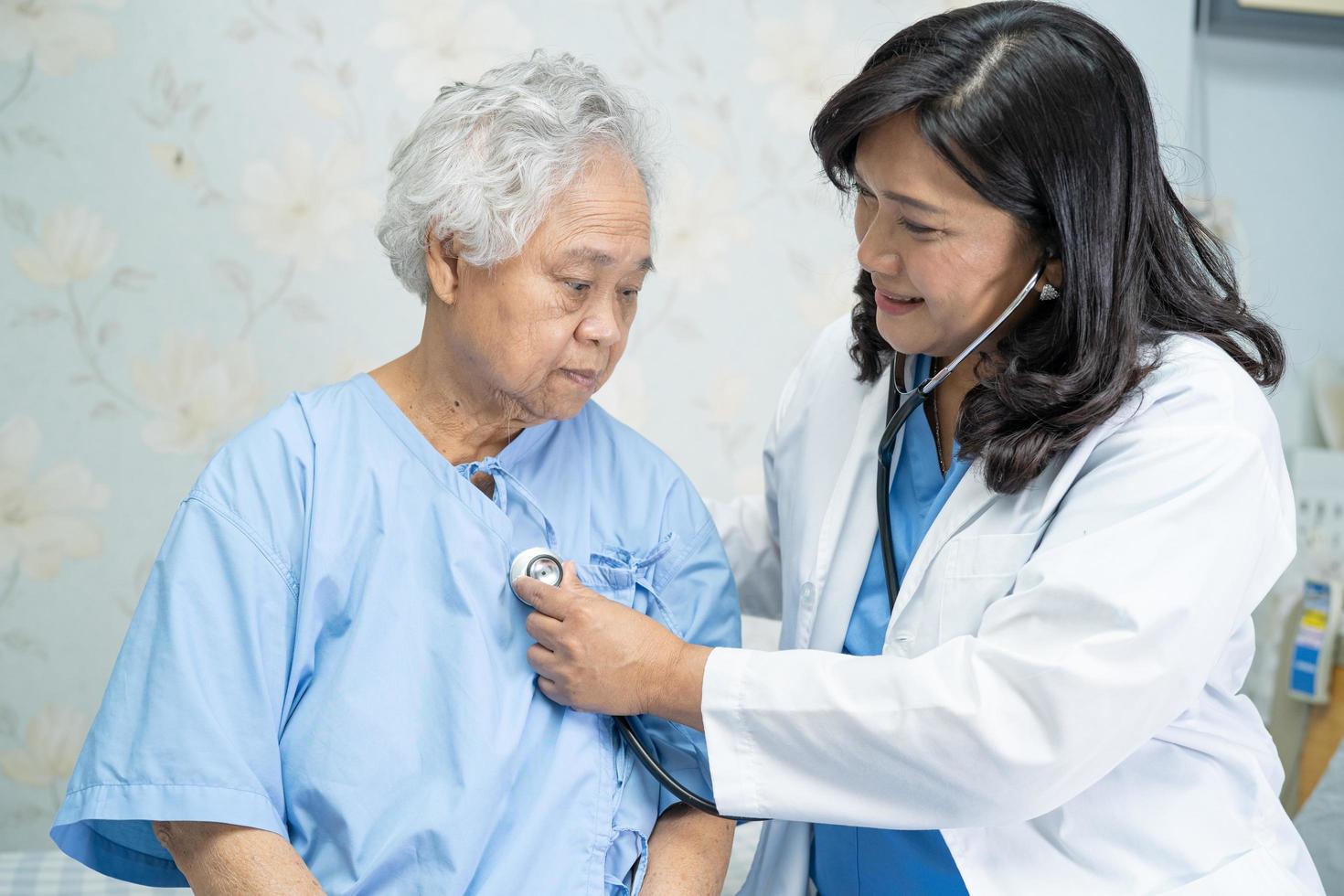 médico con estetoscopio para comprobar que el paciente se sienta en una cama en el hospital foto