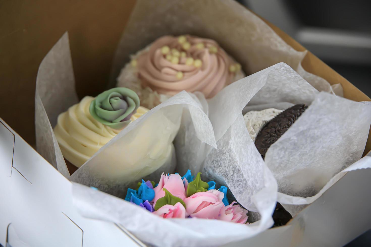 Variety of delicious cupcakes in a box from a pastry shop photo