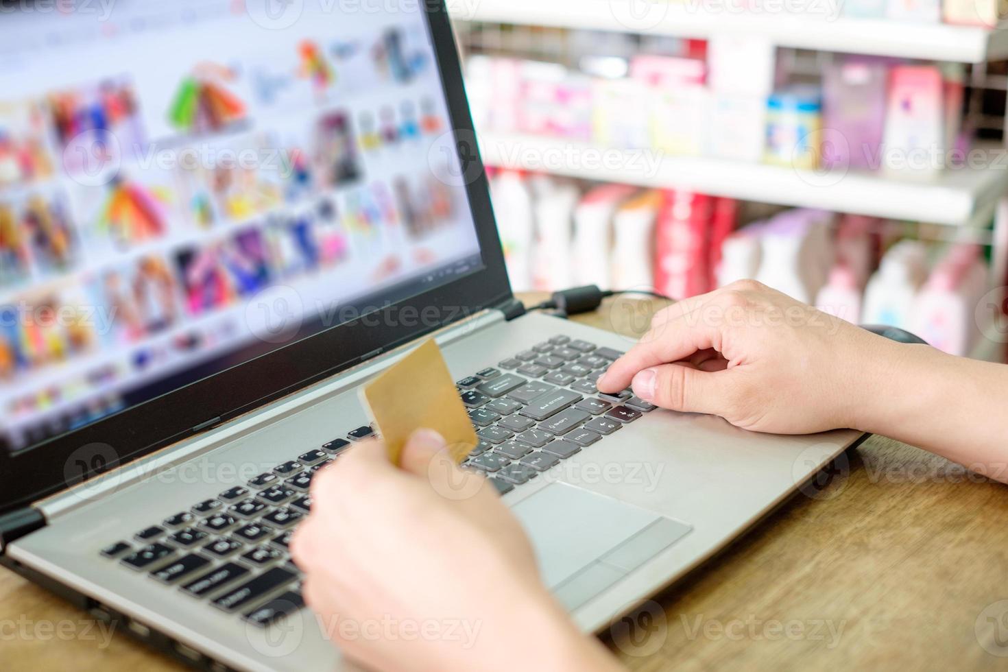 mano que sostiene la tarjeta de crédito y el uso de la computadora portátil pago compras en línea foto