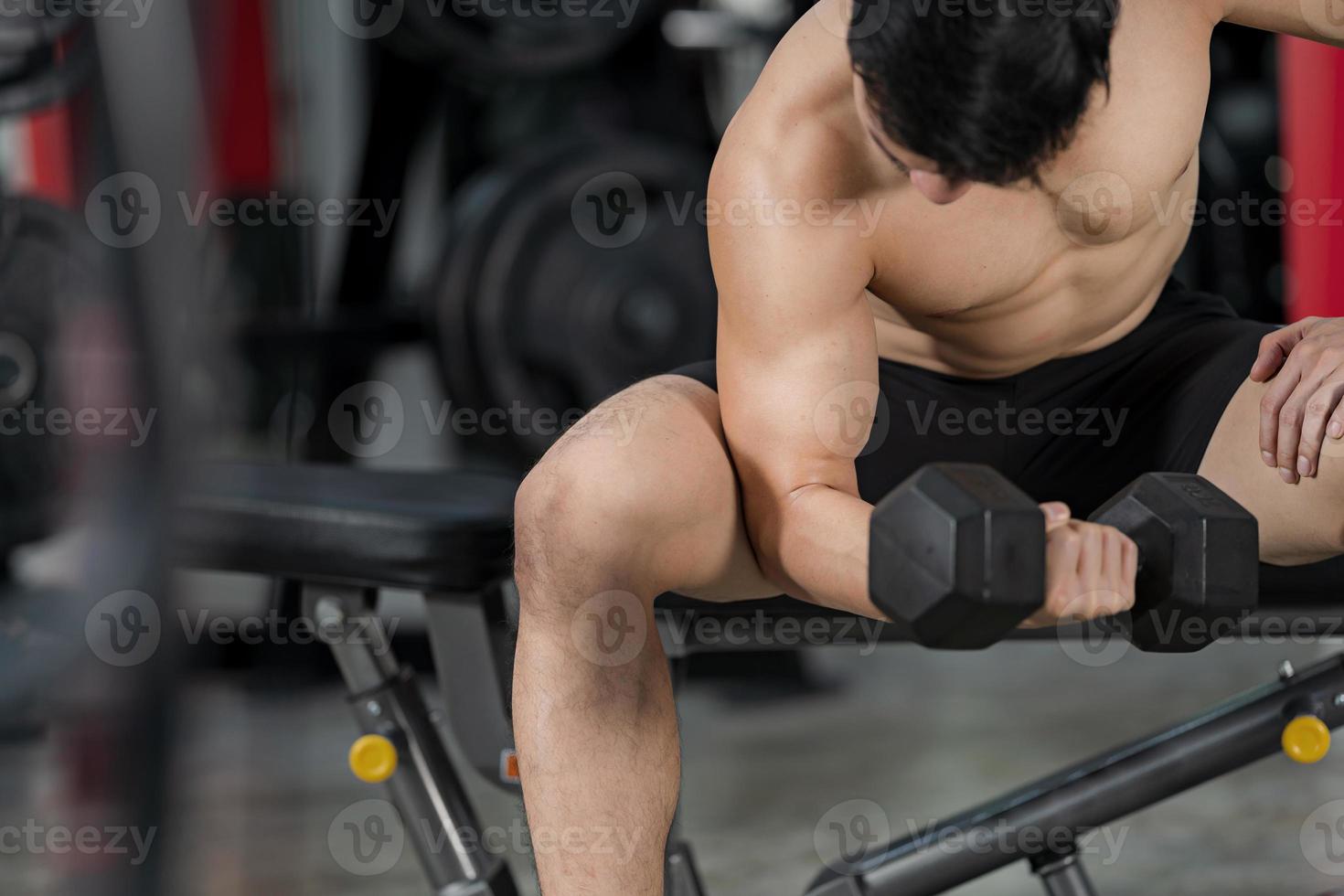 Sporty man training with dumbbell in gym photo