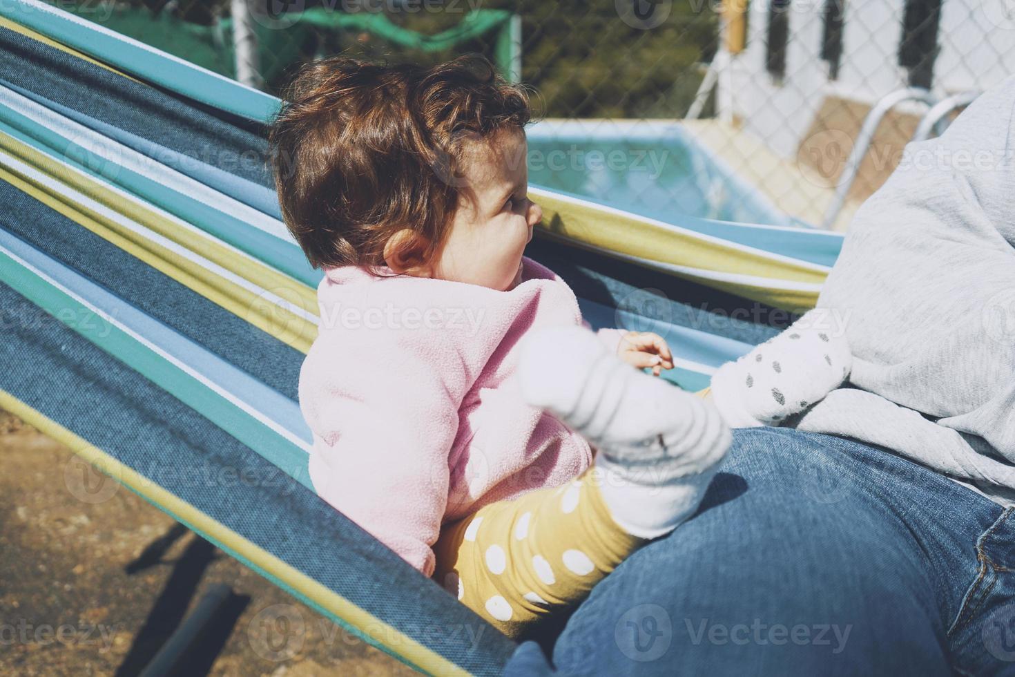 Little baby having fun on a hammock in a sunny day photo