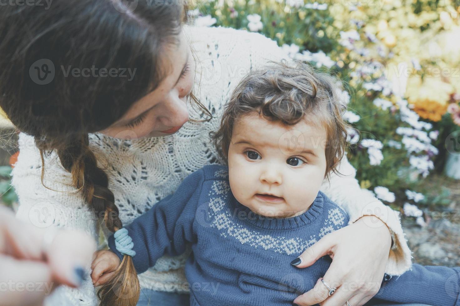 Mamá joven abrazando a su bebé y disfrutando de un día de primavera en el jardín. foto