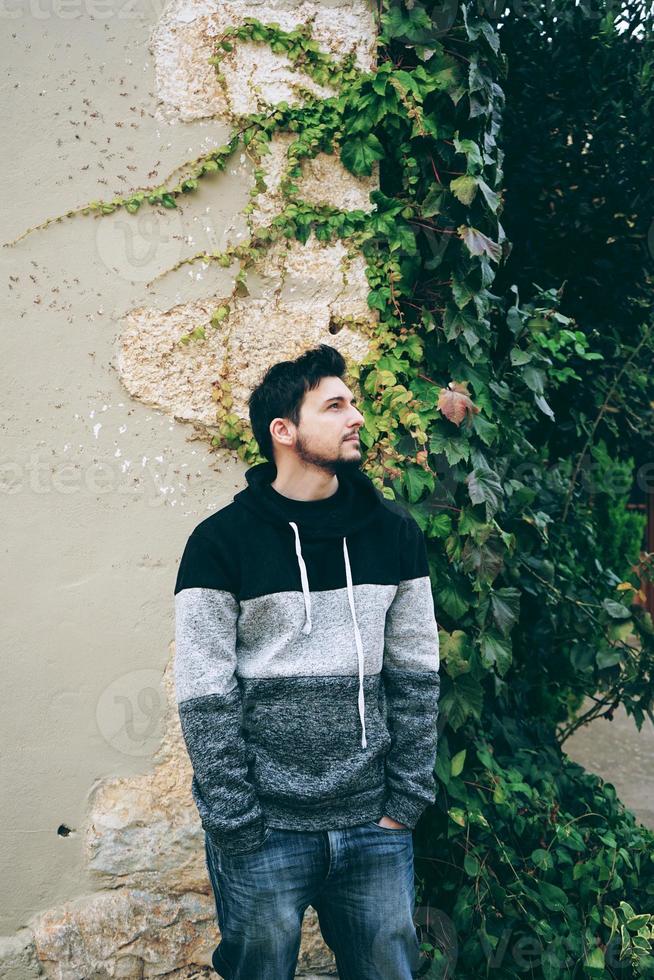 A young attractive man in calm standing with outdoor plants behind him photo