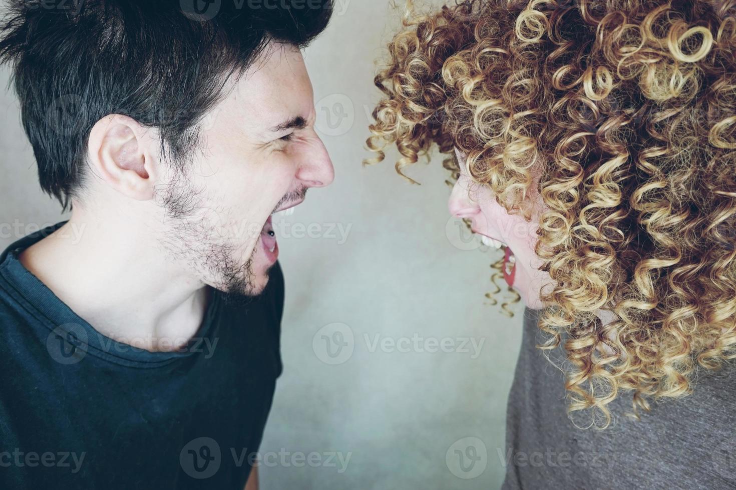 Portrait of a natural caucasian couple of young woman with curly blonde hair and man from side they shout and argue each other photo