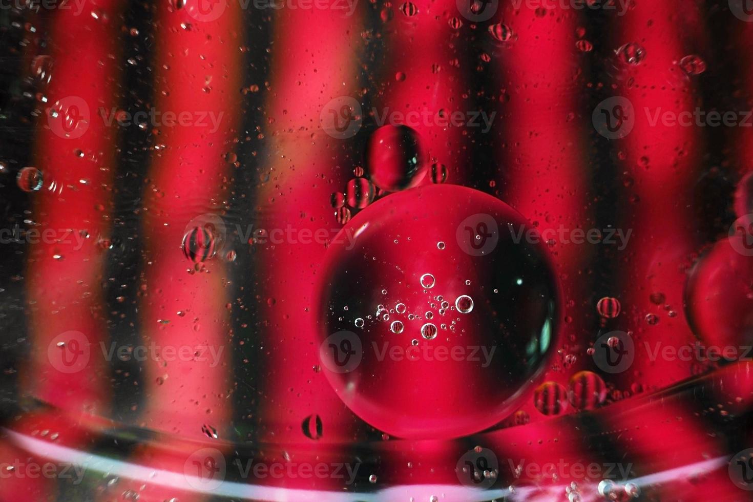 A beautiful and colorful vibrant macro of oil bubbles on water with a pink and black contrast as stripe texture and background pattern photo