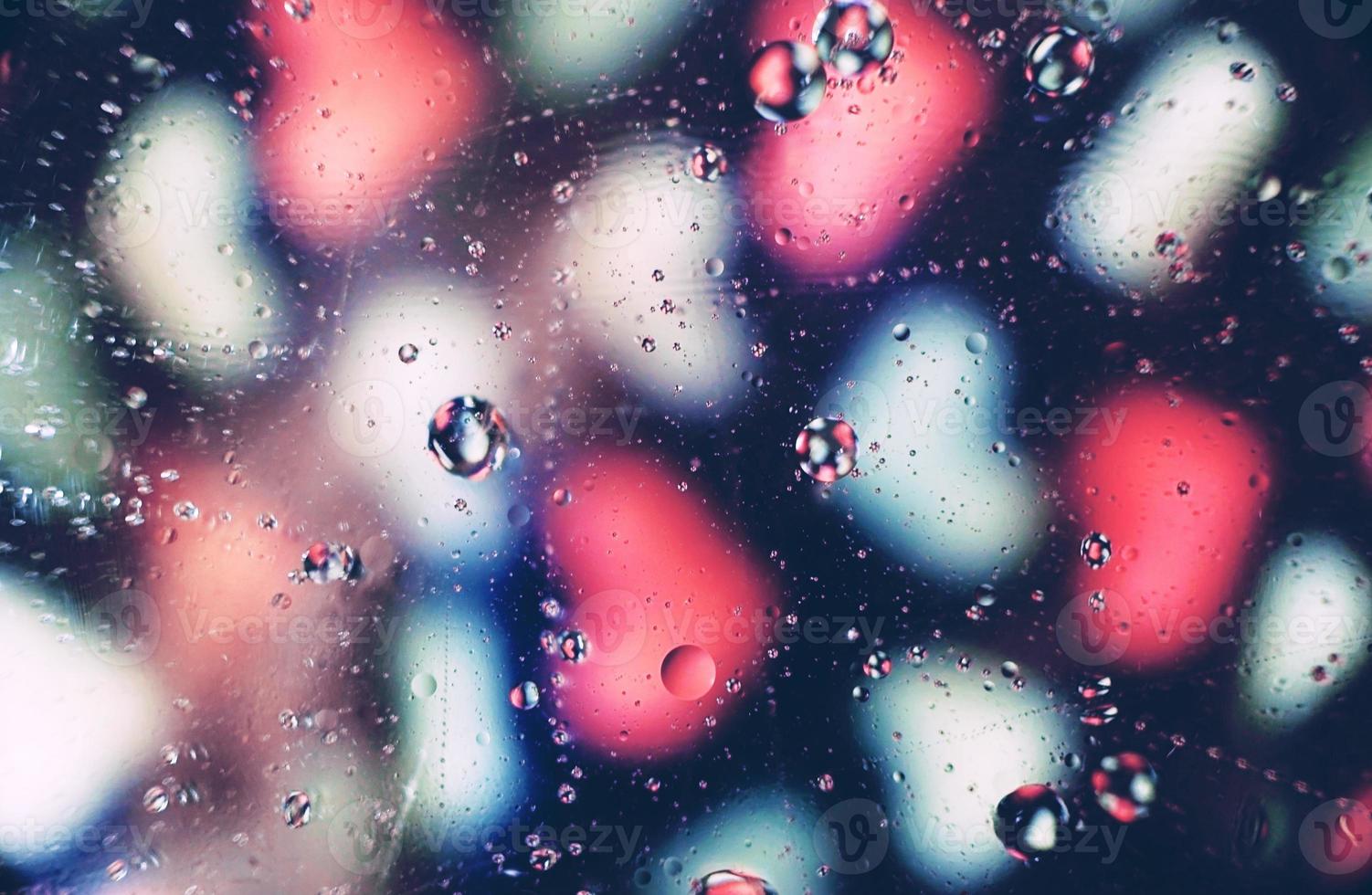 A beautiful and vibrant macro of oil bubbles on water with a blur of white and pink hearts pattern on black background photo