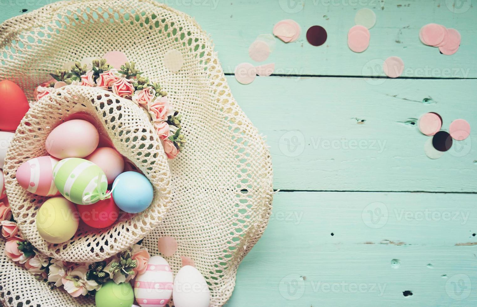 A beautiful and colorful close-up flat of easter eggs in plain pastel colors and striped in a basket with flowers and space photo