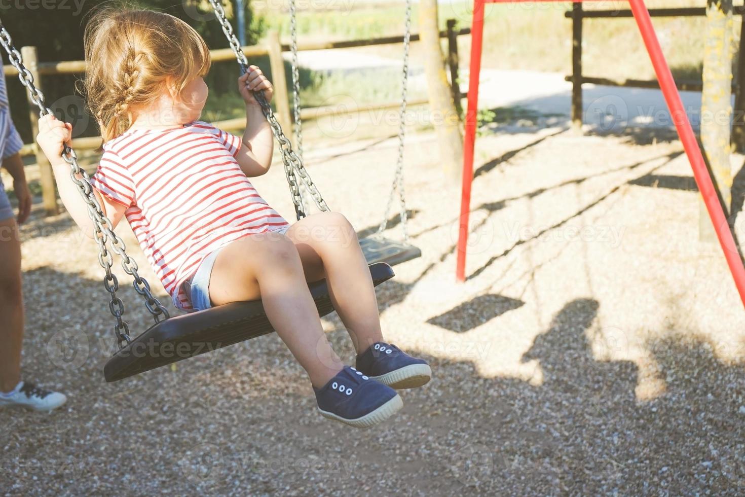Young girl in a swing at the park photo