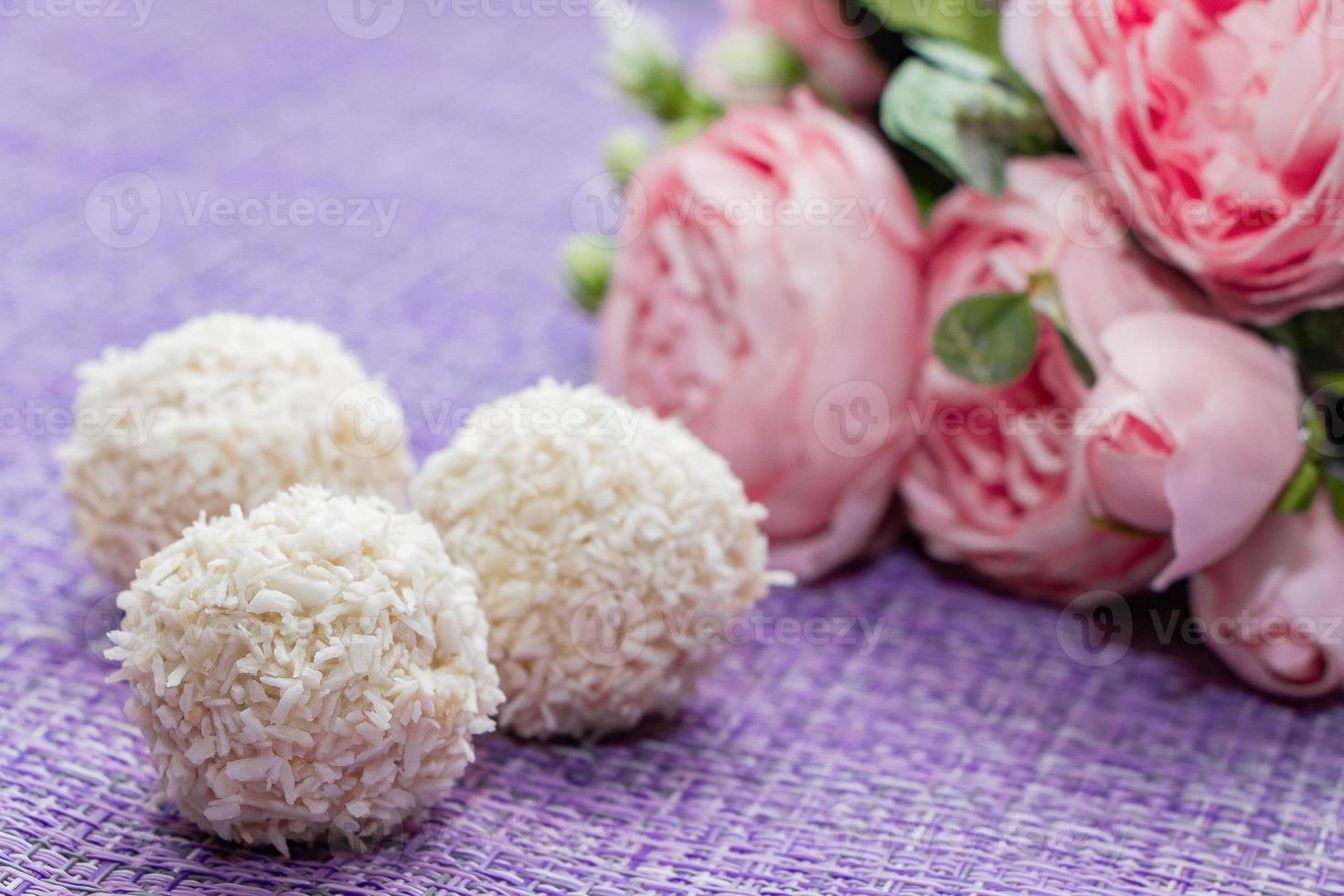 Homemade coconut candy on a background of pink flowers Sweets for Valentines Day photo