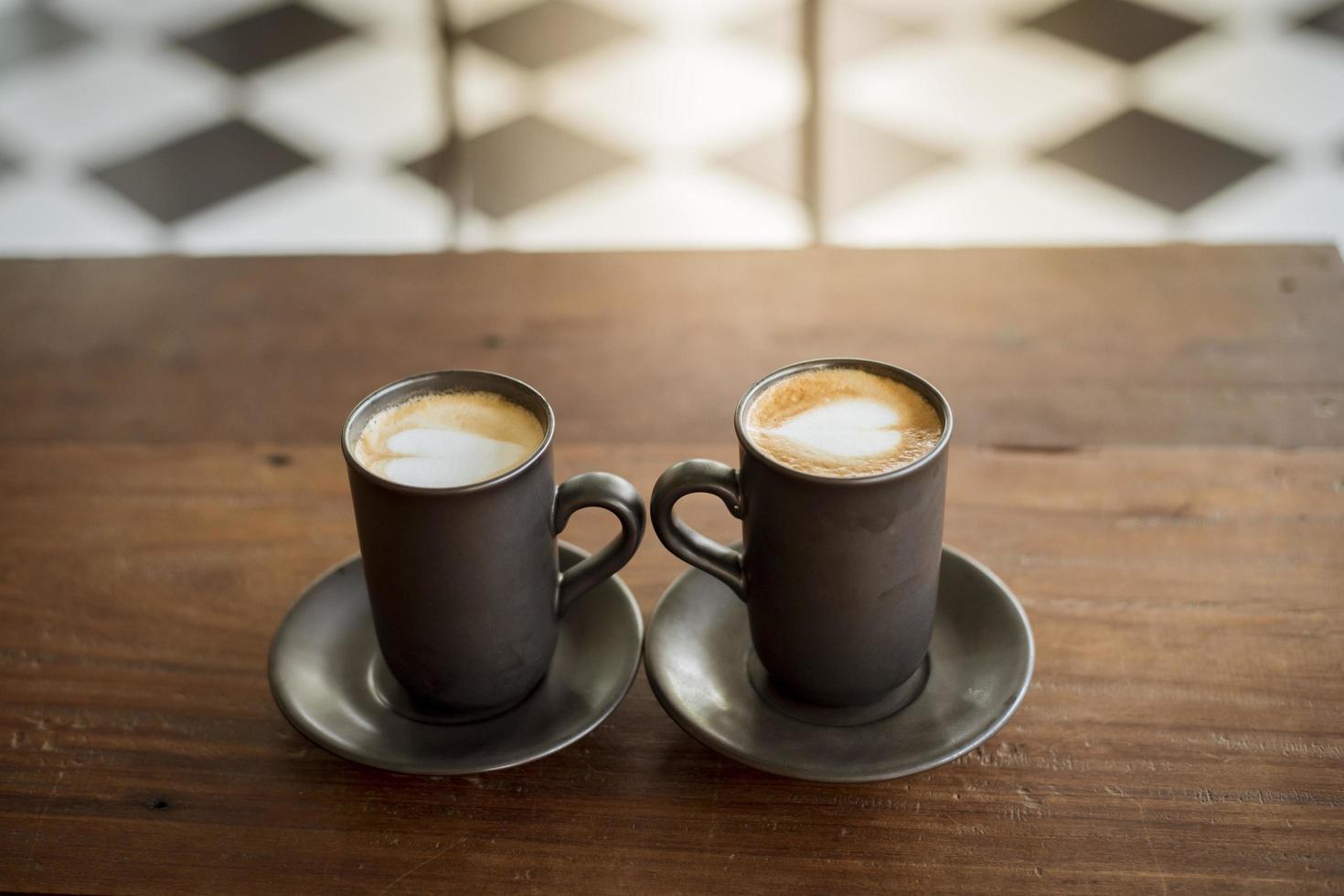 Arte latte caliente con vidrio negro sobre mesa de madera foto